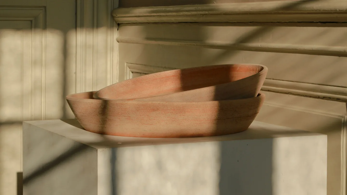 Two Rosa terracotta Bergs Potter saucers on a mantel.